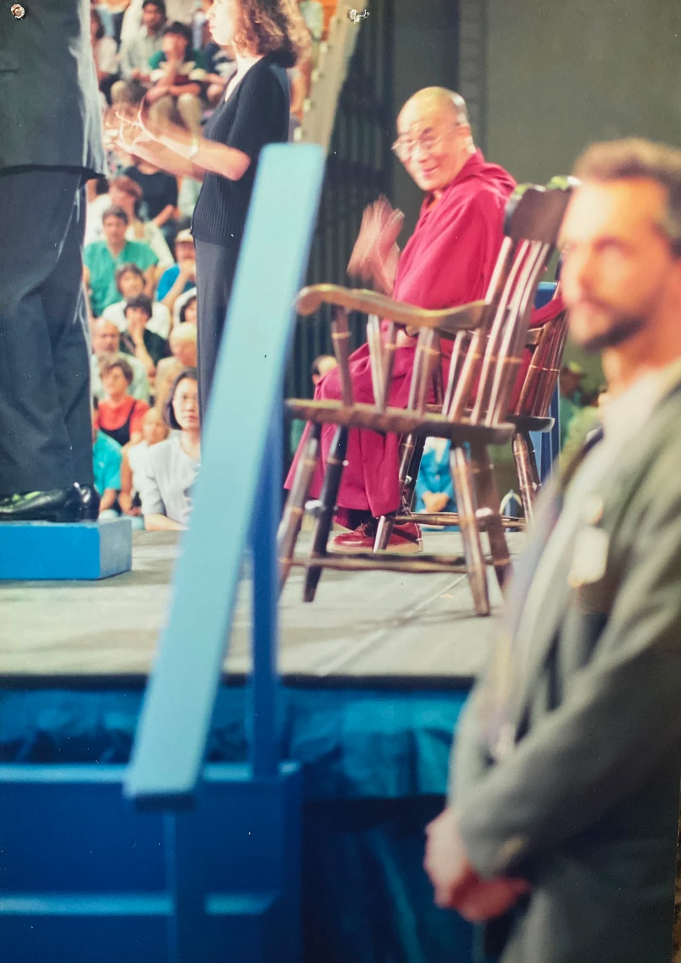 Allen Pittman steht im Vordergrund, während der Dalai Lama hinter ihm auf der Bühne sitzt